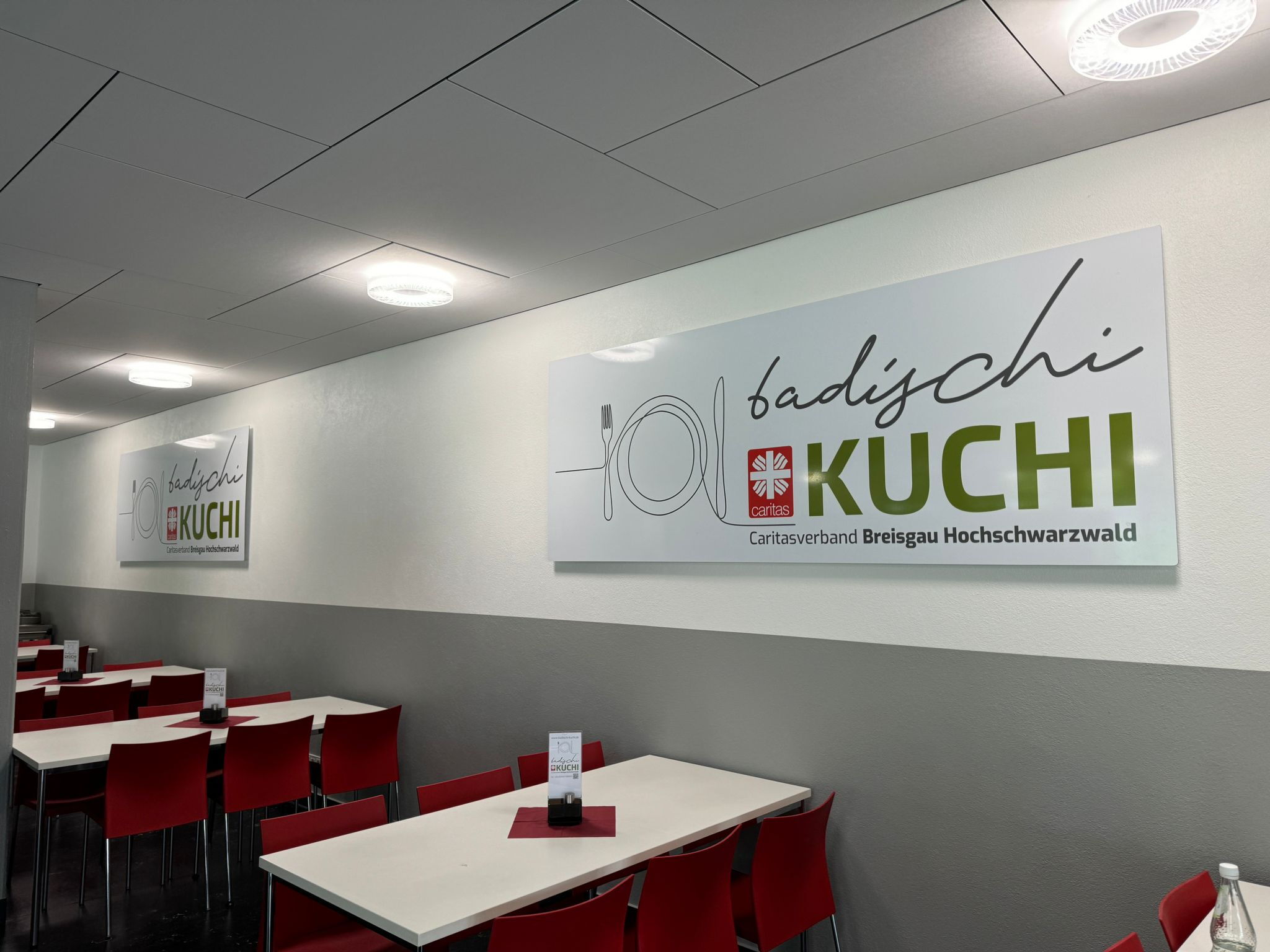 Speisesaal mit großen Logo-Tafeln „badischi Kuchi“